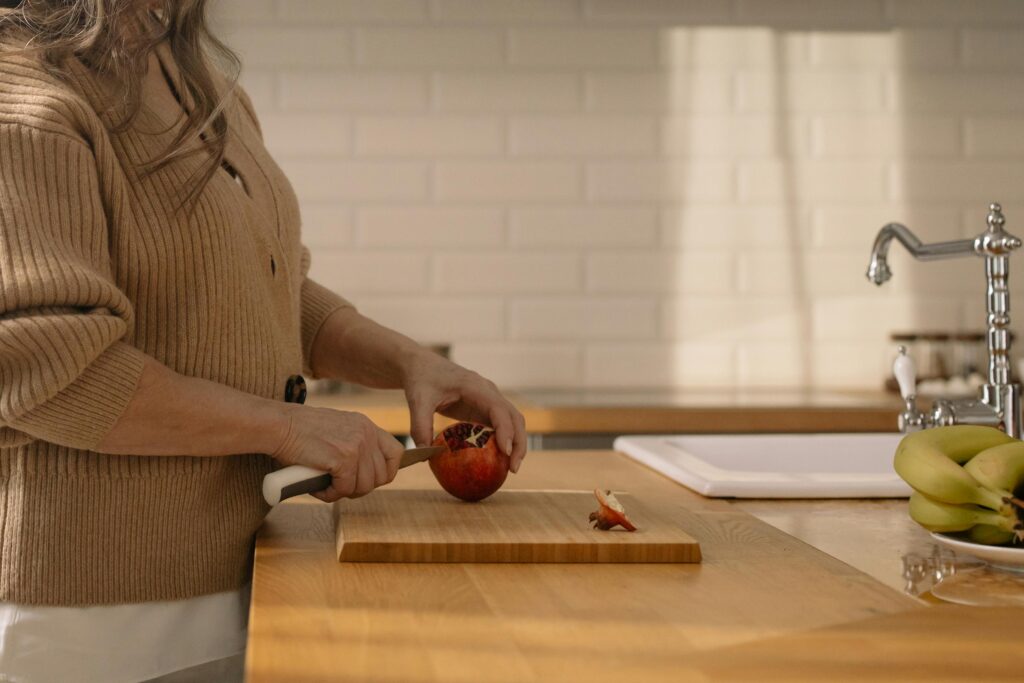 Woman Cutting Pomegranate on Wooden Chopping Board